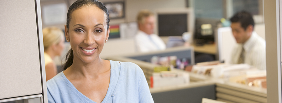 woman in doorway looking forward with other colleagues in cubicles behind her