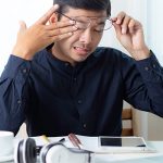 Asian male businessman with stressful headaches from working on his desk.