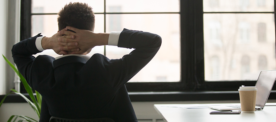 Rear view at relaxed businessman in suit enjoying break resting from work on laptop, man in suit holding hands behind head feeling no stress free relief relaxing or thinking planning future in office